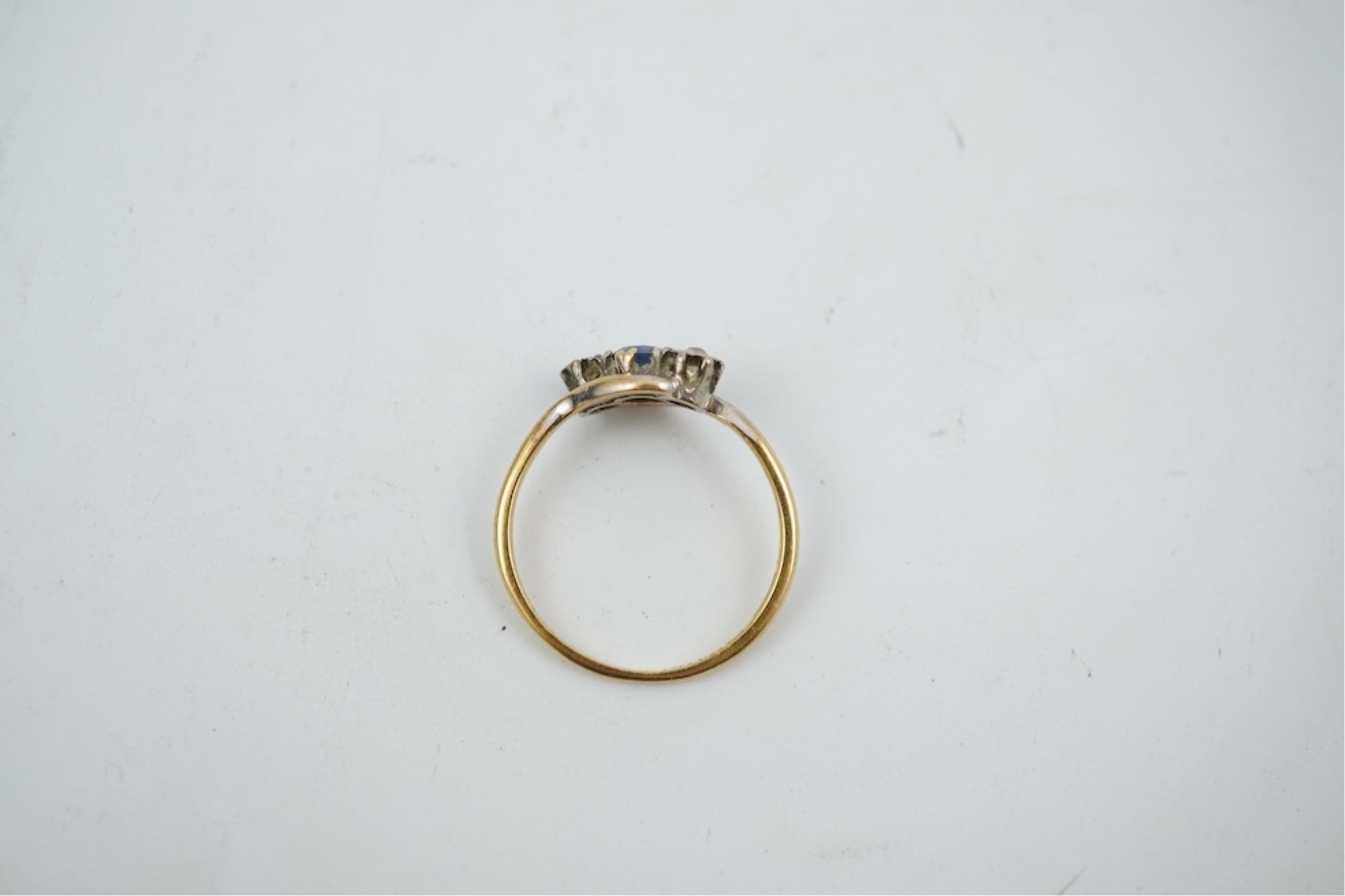 An early 20th century 18ct gold, sapphire and diamond set three stone crossover ring, size P/Q, gross weight 2.4 grams.
